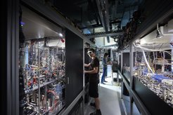 Quantum gas microscope at MPQ. The system consists of the two densely packed optical tables, the electronics in the background and a control centre which is not visible in the picture.