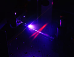 Generation of attosecond pulses in a jet of neon gas within the enhancement resonator cavity. The excitation of the gas atoms makes the intersecting infrared laser beams (shown in red) in the resonator visible to the human eye. Photo: Thorsten Naeser