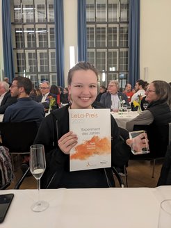 Sofie Silbermann, Werkstudentin des PhotonLab, war für die Konzeption des Experiments verantwortlich. Hier zeigt sie stolz die Siegerurkunde.